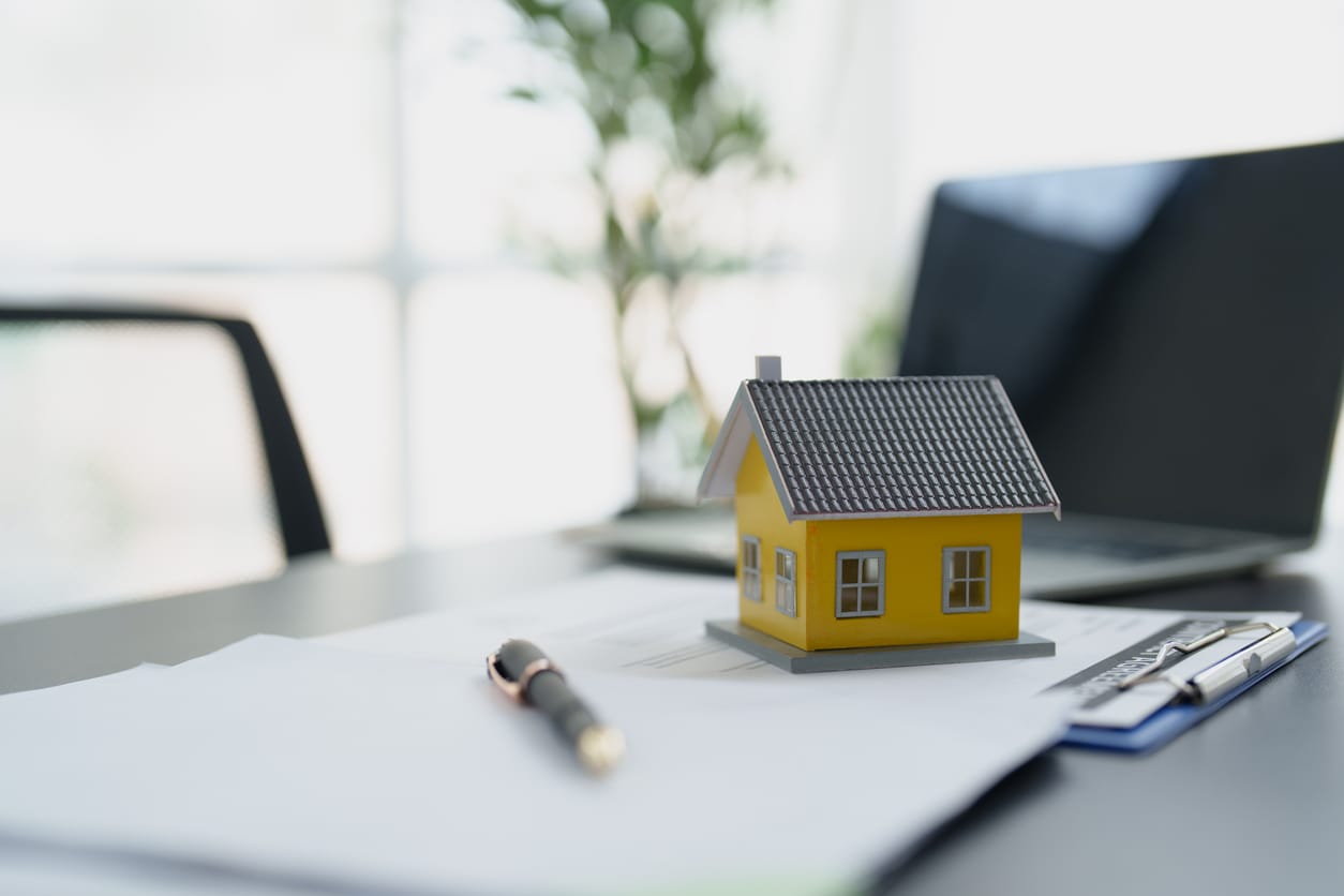 Model house, lease paperwork, and a pen on a property manager's desk
