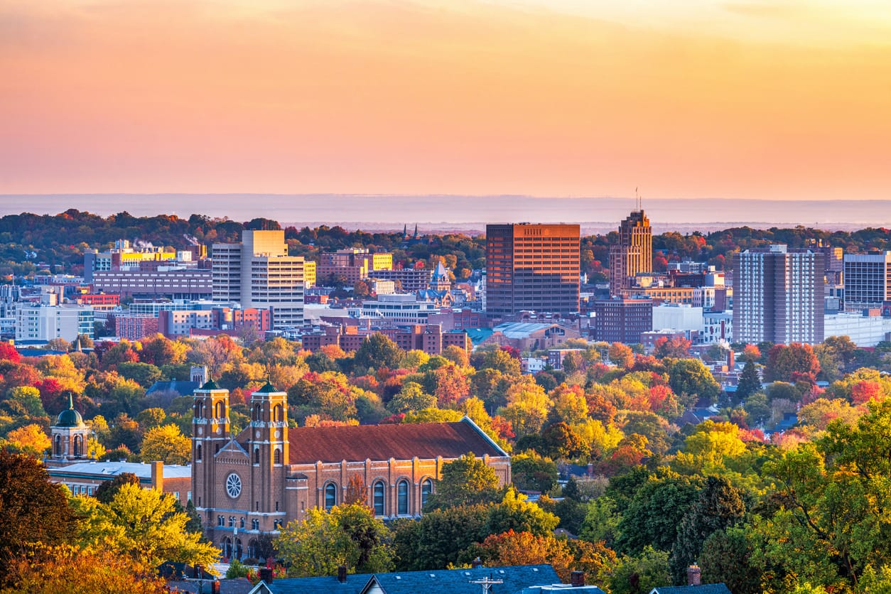 Upstate New York city skyline surrounded by autumn trees at sunset